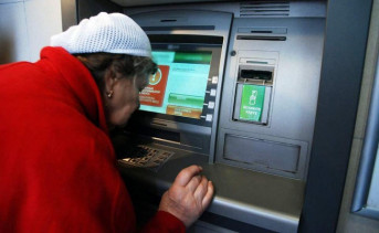 Пенсионерка проверяет баланс карты в банкомате. Фото yur–gazeta.ru